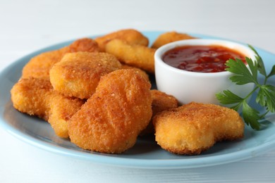 Photo of Tasty chicken nuggets with chili sauce and parsley on white table, closeup