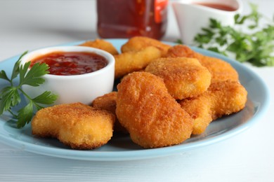 Photo of Tasty chicken nuggets with chili sauce and parsley on white table, closeup