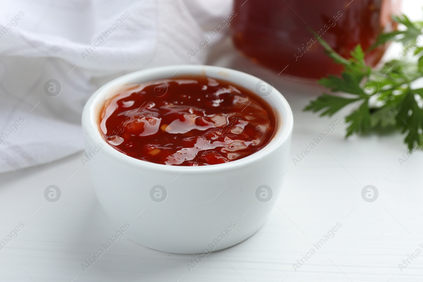 Photo of Spicy chili sauce in bowl on white wooden table, closeup