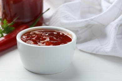 Photo of Spicy chili sauce in bowl on white wooden table, closeup