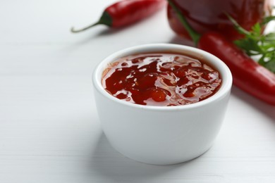 Photo of Spicy chili sauce in bowl on white wooden table, closeup