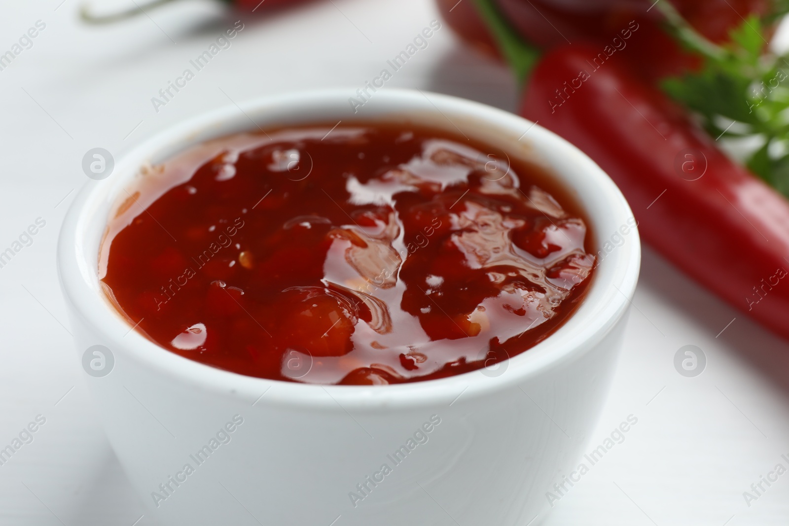 Photo of Spicy chili sauce in bowl on white table, closeup