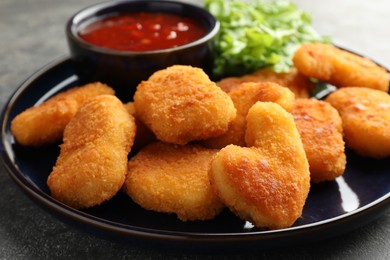 Photo of Tasty chicken nuggets with chili sauce on grey table, closeup