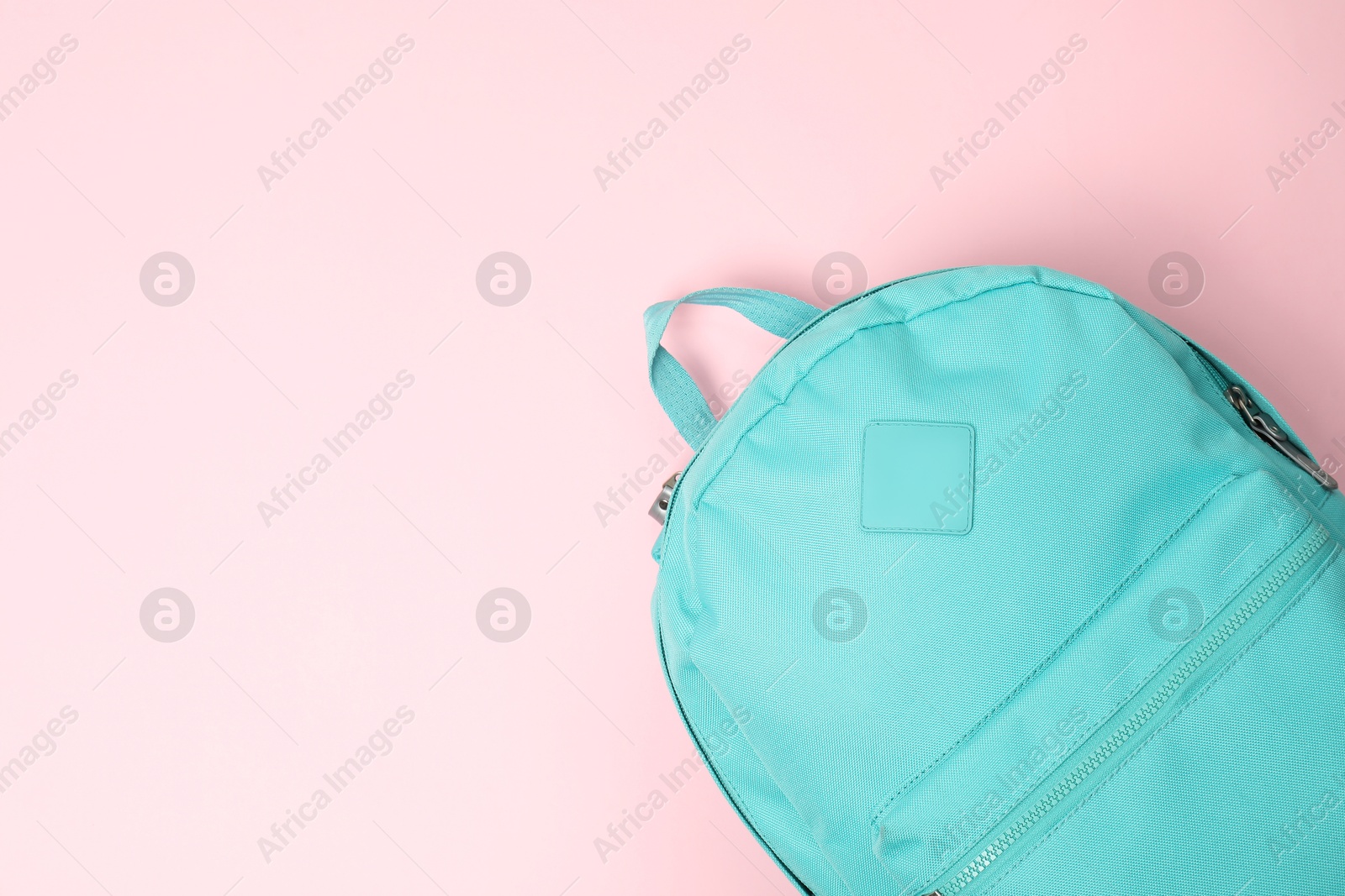 Photo of One turquoise backpack on pink background, top view. Space for text