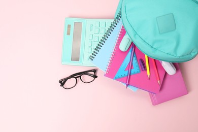 Photo of Backpack with different school stationery on pink background, flat lay