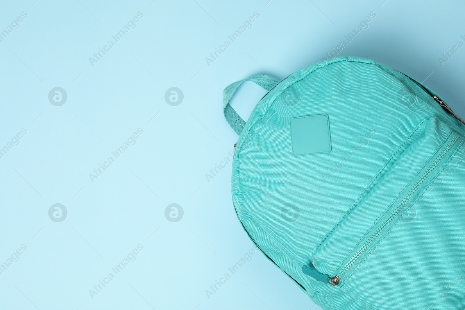 Photo of One bright backpack on light blue background, top view. Space for text