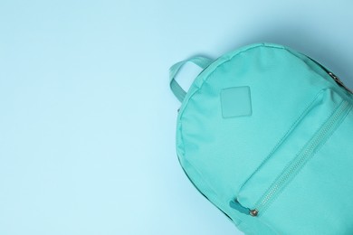 Photo of One bright backpack on light blue background, top view. Space for text