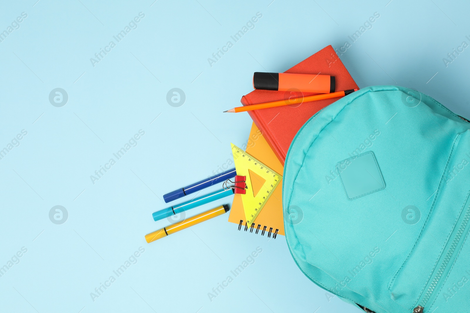 Photo of Backpack with different school stationery on light blue background, flat lay. Space for text