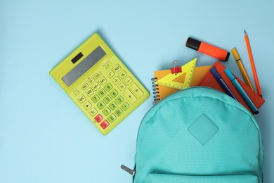 Photo of Backpack with different school stationery on light blue background, flat lay