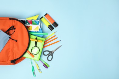 Photo of Orange backpack and different school supplies on light blue background, flat lay. Space for text