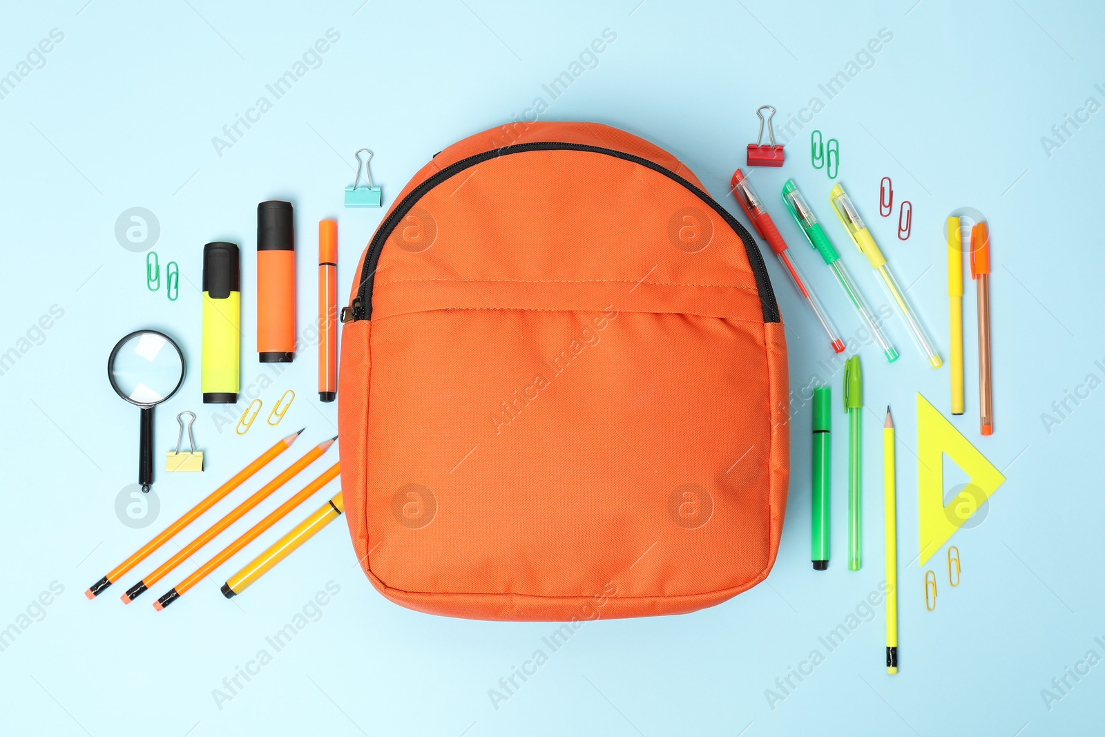 Photo of Orange backpack and different school supplies on light blue background, flat lay