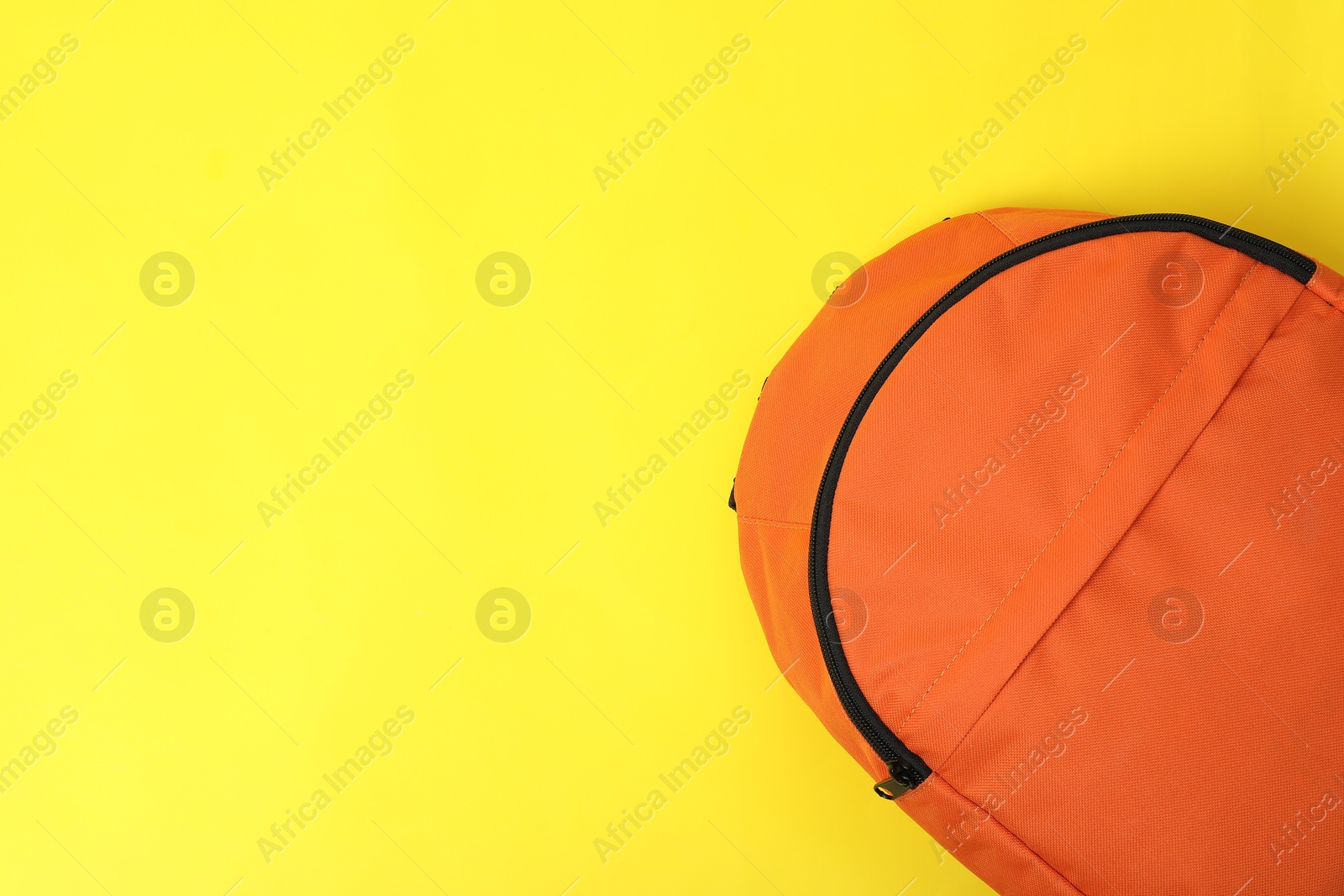 Photo of One orange backpack on yellow background, top view. Space for text