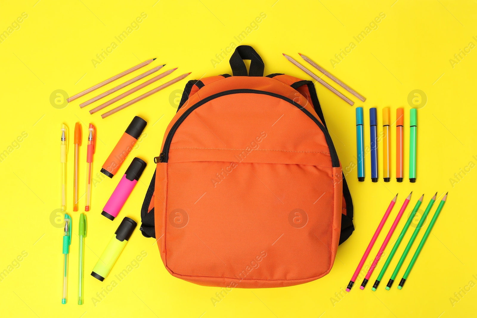 Photo of Orange backpack and different school stationery on yellow background, flat lay