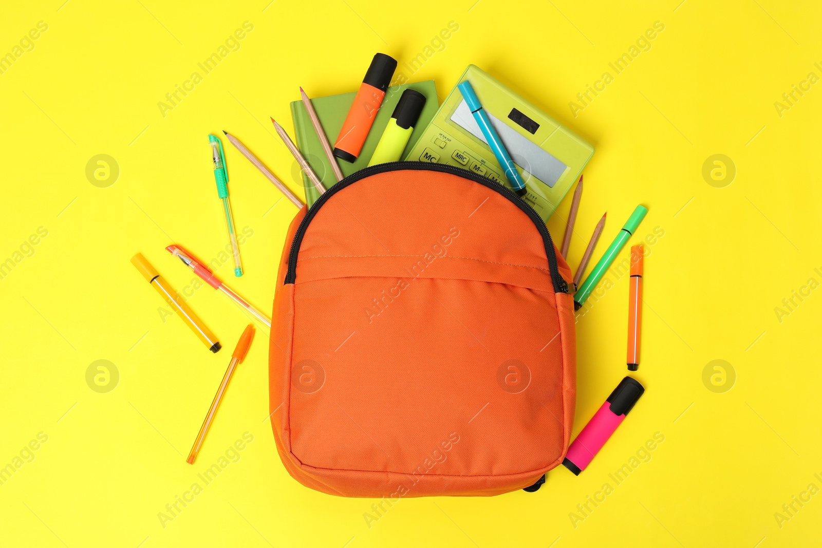 Photo of Orange backpack and different school supplies on yellow background, flat lay