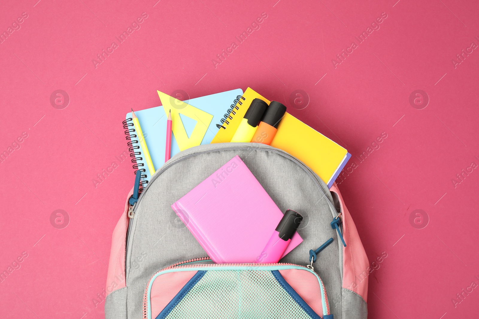 Photo of Backpack with different school supplies on pink background, top view