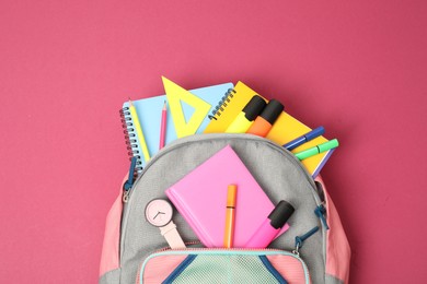 Photo of Backpack with different school supplies on pink background, top view