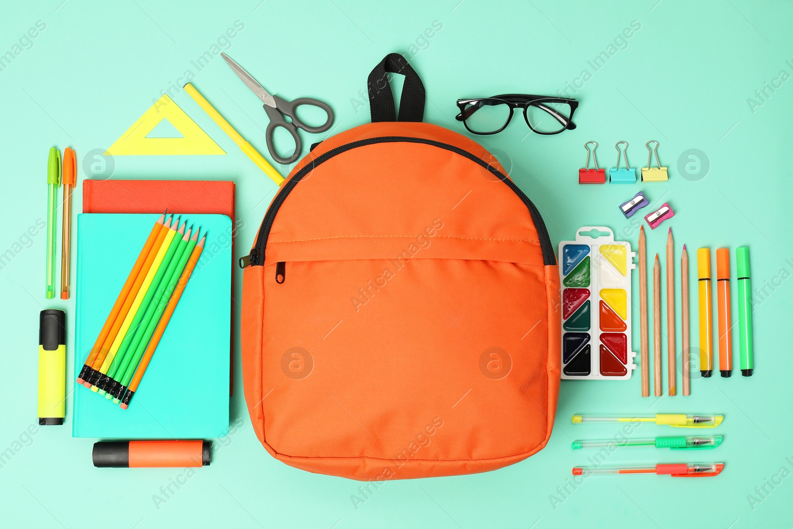 Photo of Backpack and different school supplies on turquoise background, flat lay