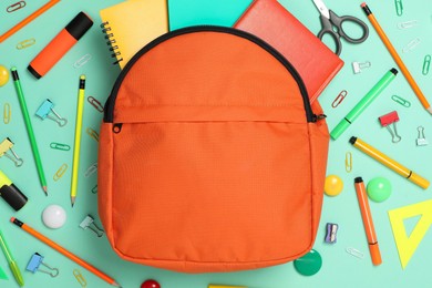 Backpack and different school supplies on turquoise background, flat lay