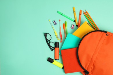 Photo of Backpack and different school supplies on turquoise background, flat lay. Space for text