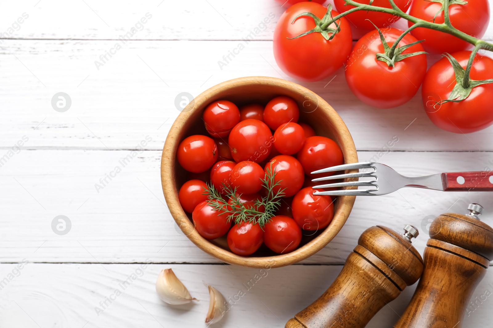 Photo of Tasty pickled tomatoes, fresh vegetables, dill, garlic and fork on white wooden table, top view. Space for text