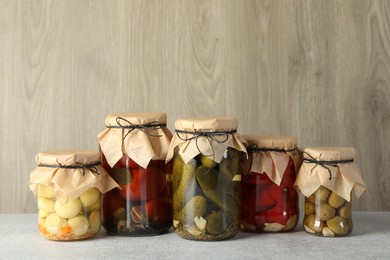 Photo of Different pickled products in jars on grey table