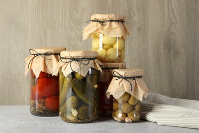 Photo of Different pickled products in jars on grey table