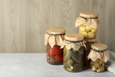 Photo of Different pickled products in jars on grey table, space for text