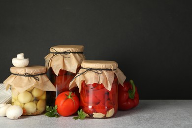 Photo of Different pickled products in jars and fresh ingredients on grey table