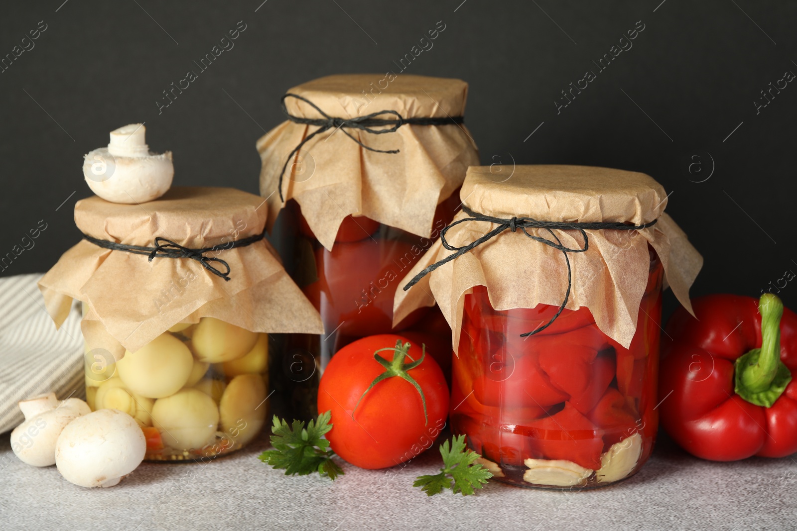 Photo of Different pickled products in jars and fresh ingredients on grey table