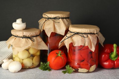 Photo of Different pickled products in jars and fresh ingredients on grey table