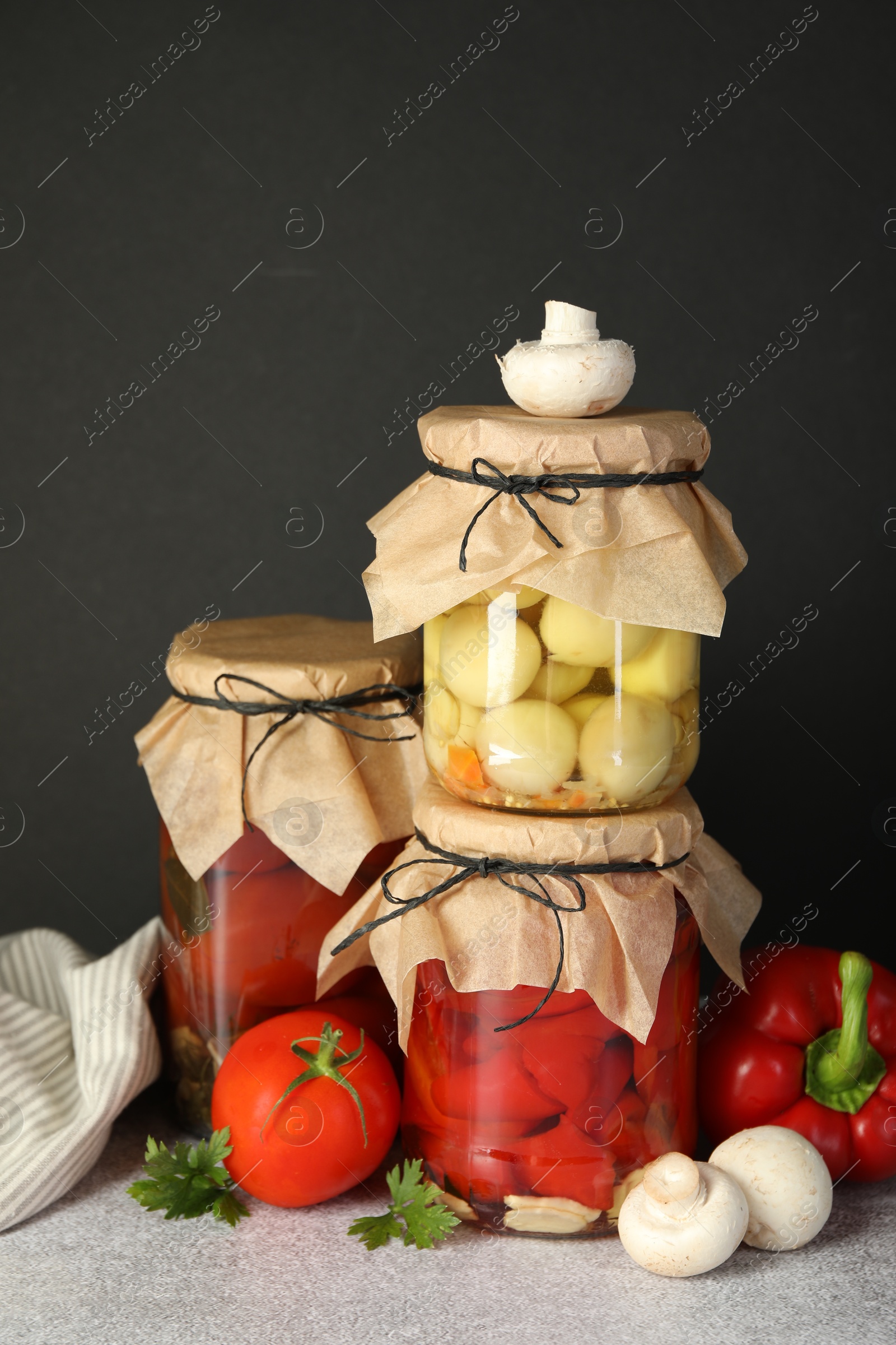 Photo of Different pickled products in jars and fresh ingredients on grey table