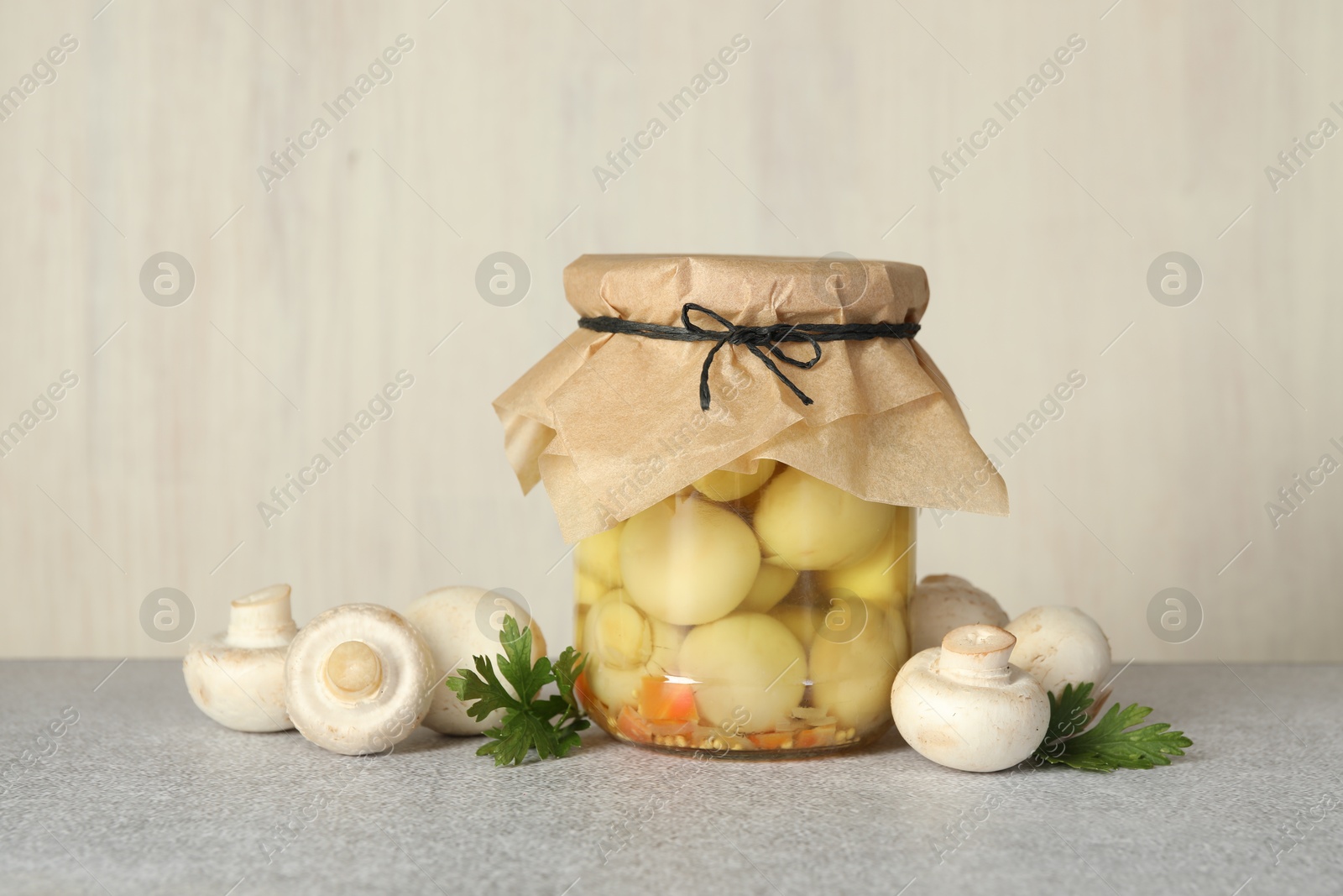 Photo of Tasty pickled mushrooms in jar and fresh ingredients on grey table