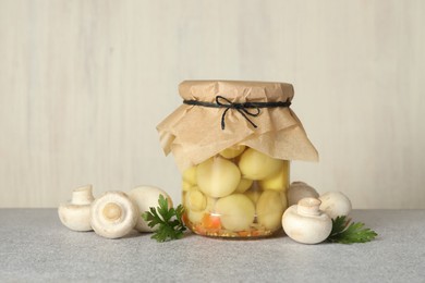 Photo of Tasty pickled mushrooms in jar and fresh ingredients on grey table