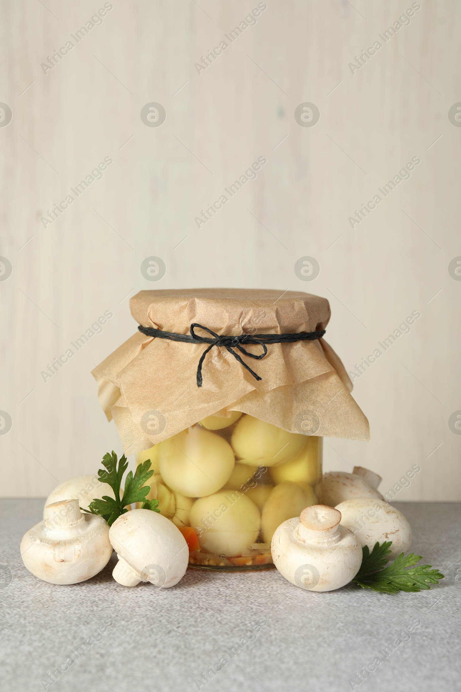 Photo of Tasty pickled mushrooms in jar and fresh ingredients on grey table