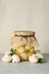 Photo of Tasty pickled mushrooms in jar and fresh ingredients on grey table