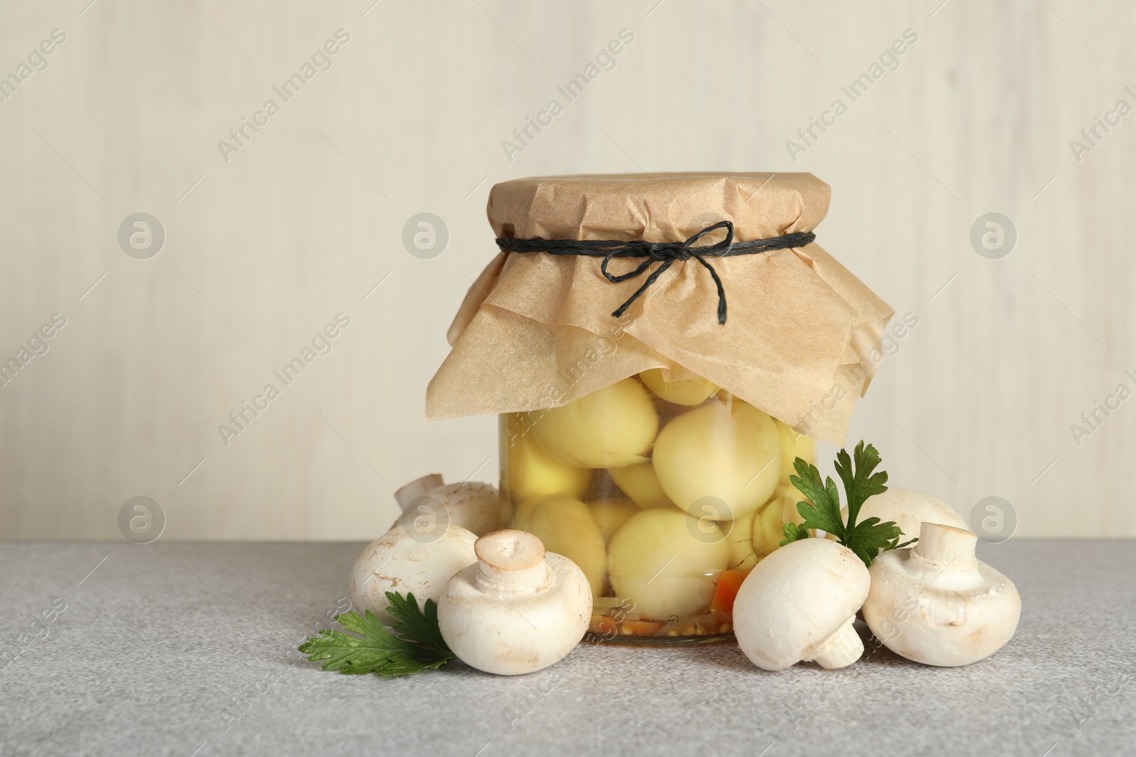 Photo of Tasty pickled mushrooms in jar and fresh ingredients on grey table