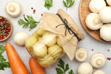 Photo of Tasty pickled mushrooms in jar and fresh ingredients on grey table, flat lay