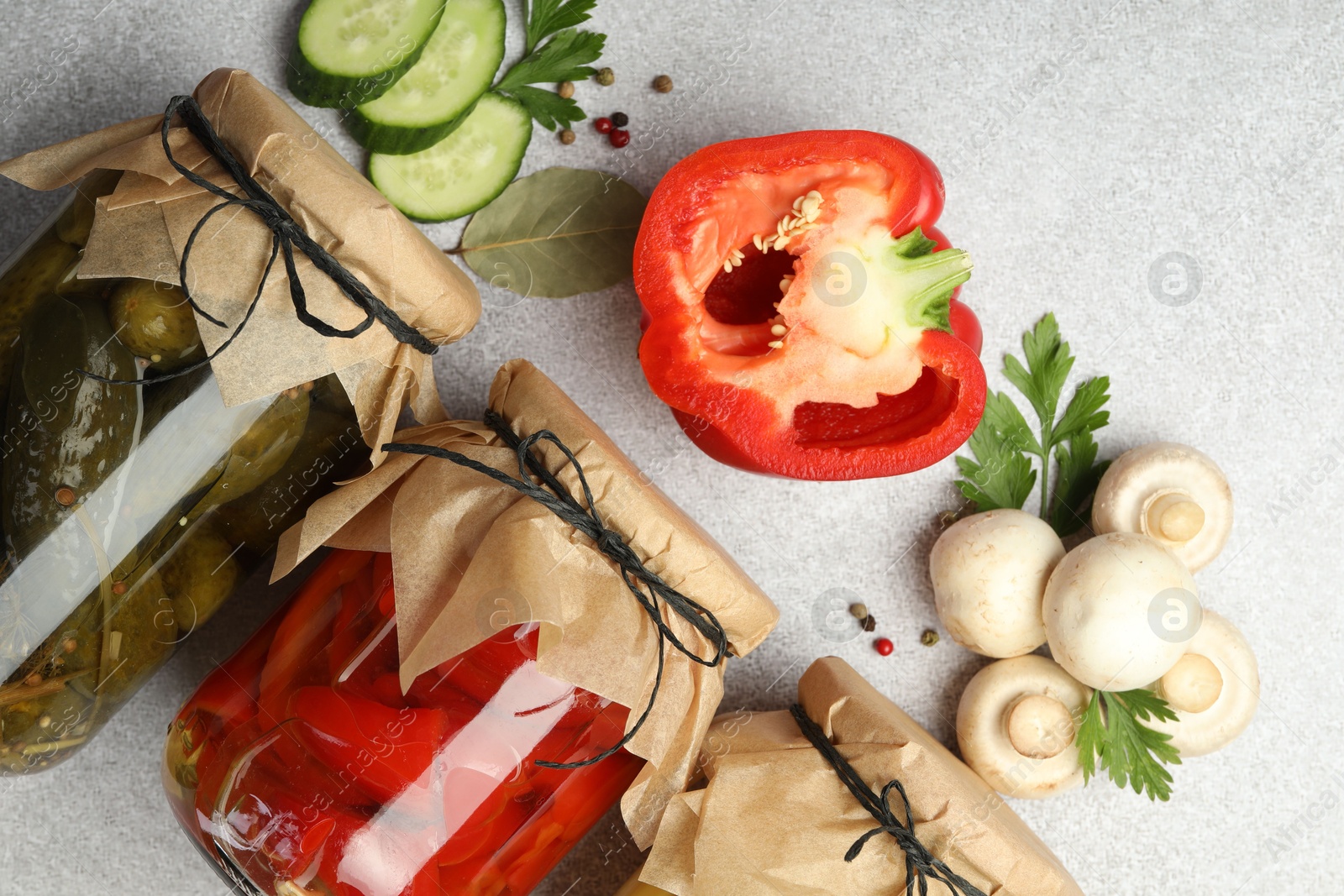 Photo of Different pickled products in jars and fresh ingredients on grey table, flat lay