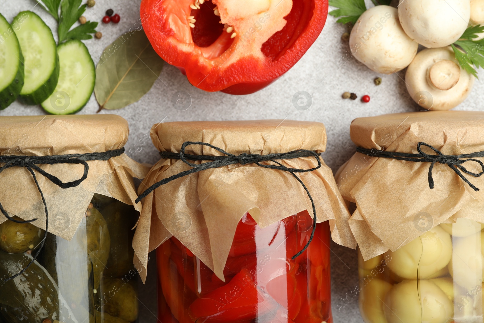 Photo of Different pickled products in jars and fresh ingredients on grey table, flat lay