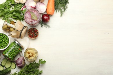 Photo of Different pickled products in jars and fresh ingredients on white wooden table, flat lay. Space for text