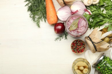 Photo of Different pickled products in jars and fresh ingredients on white wooden table, flat lay. Space for text