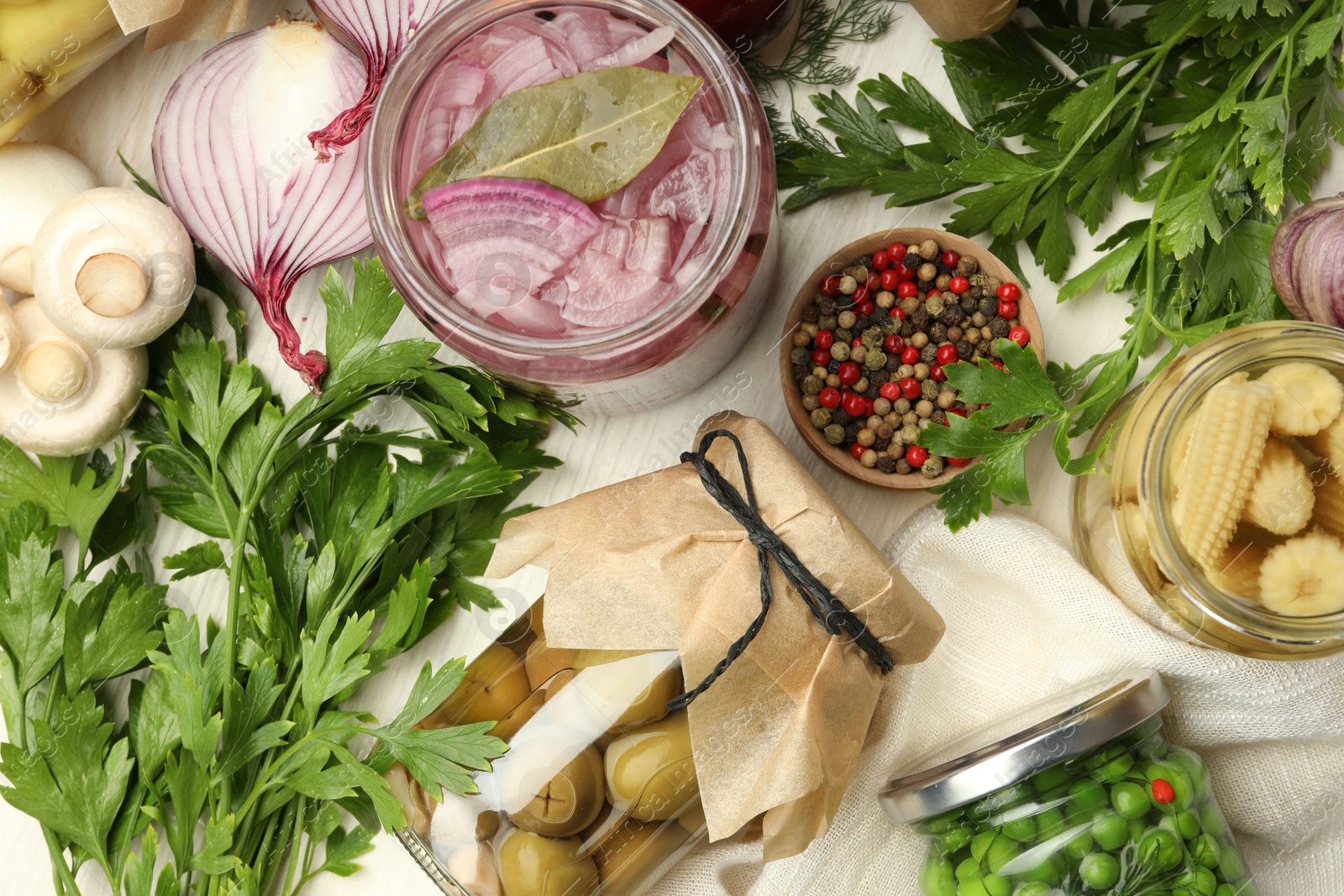 Photo of Different pickled products in jars and fresh ingredients on white table, flat lay