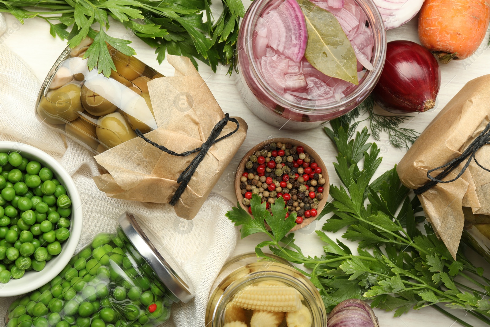 Photo of Different pickled products in jars and fresh ingredients on white table, flat lay