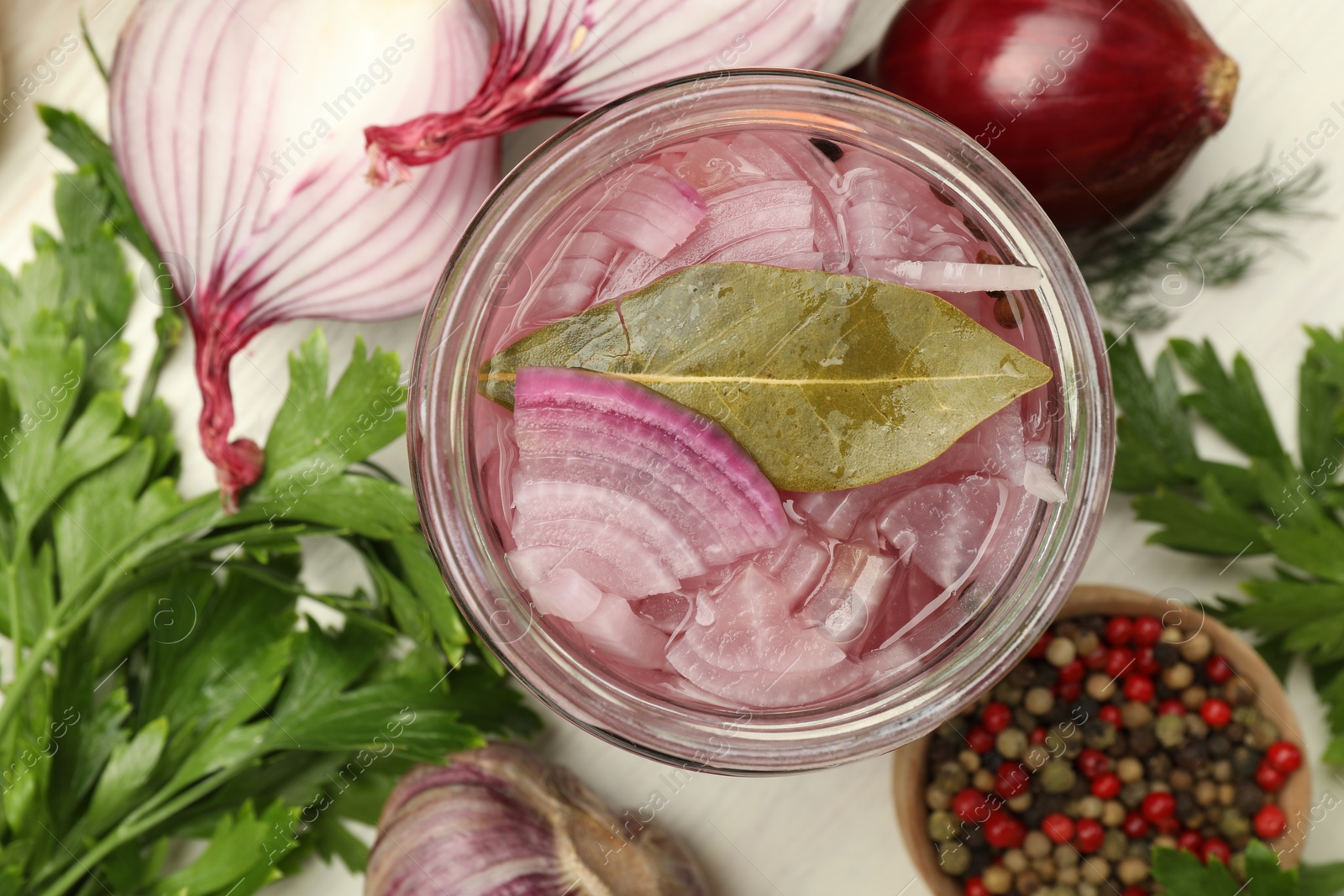 Photo of Tasty pickled onion in jar and fresh ingredients on white table, flat lay