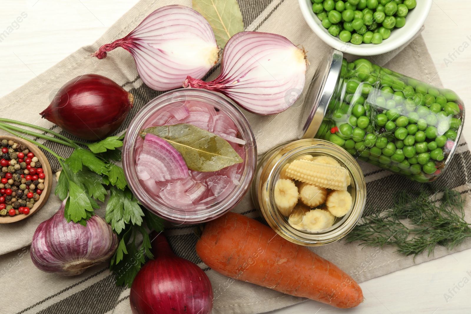 Photo of Different pickled products in jars and fresh ingredients on white table, flat lay