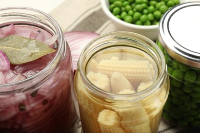 Photo of Different pickled products in jars on table, closeup