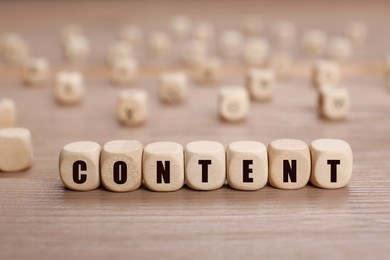 Word Content made of cubes with letters on wooden table, closeup