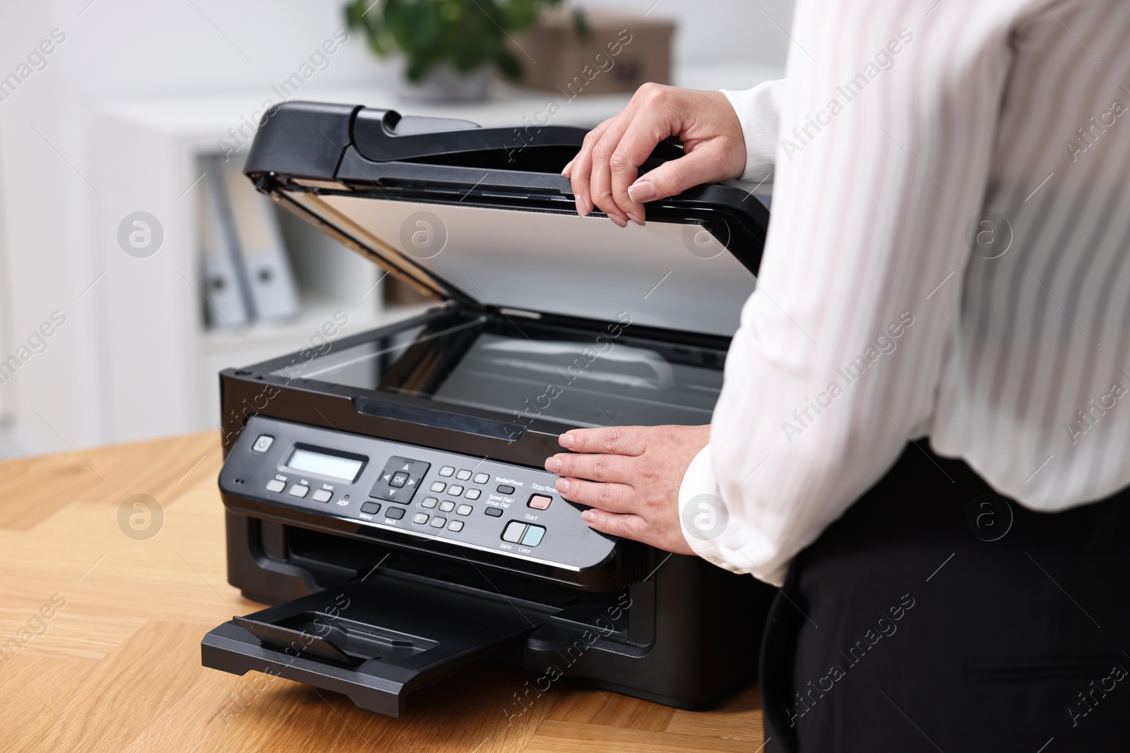 Photo of Woman using modern printer at workplace indoors, closeup