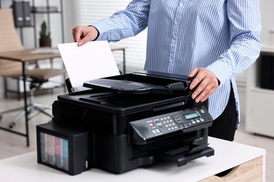 Photo of Woman using modern printer at workplace indoors, closeup