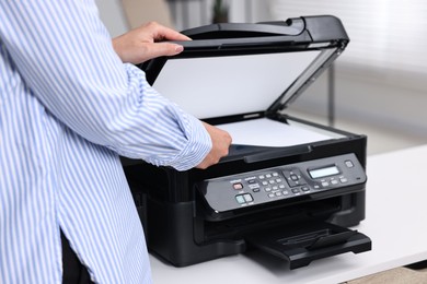 Photo of Woman using modern printer at workplace indoors, closeup